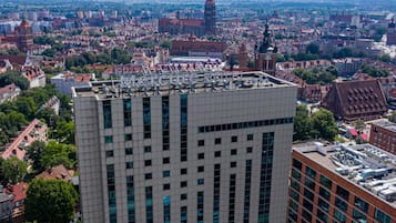 A high-rise hotel with a modern facade, large windows, and a rooftop terrace.