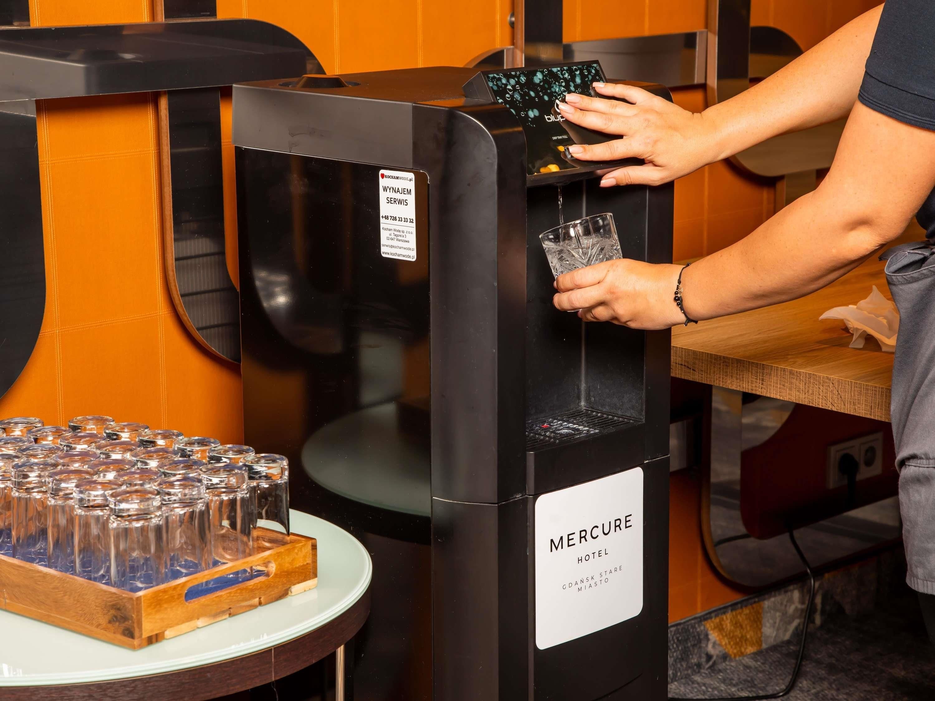 A person using a water dispenser at a hotel.