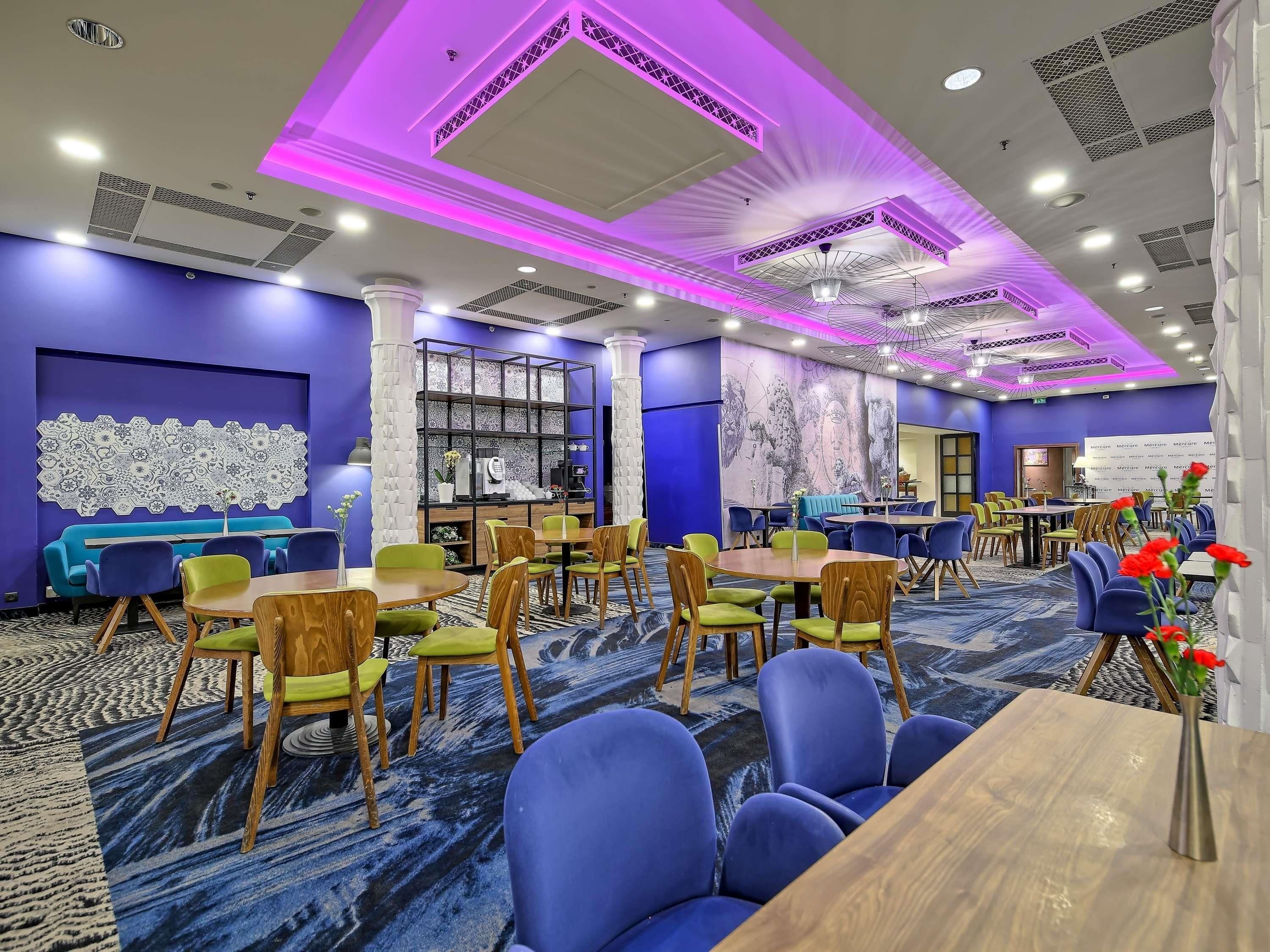 A hotel dining area with tables and chairs, a coffee station, and decorative wall art.