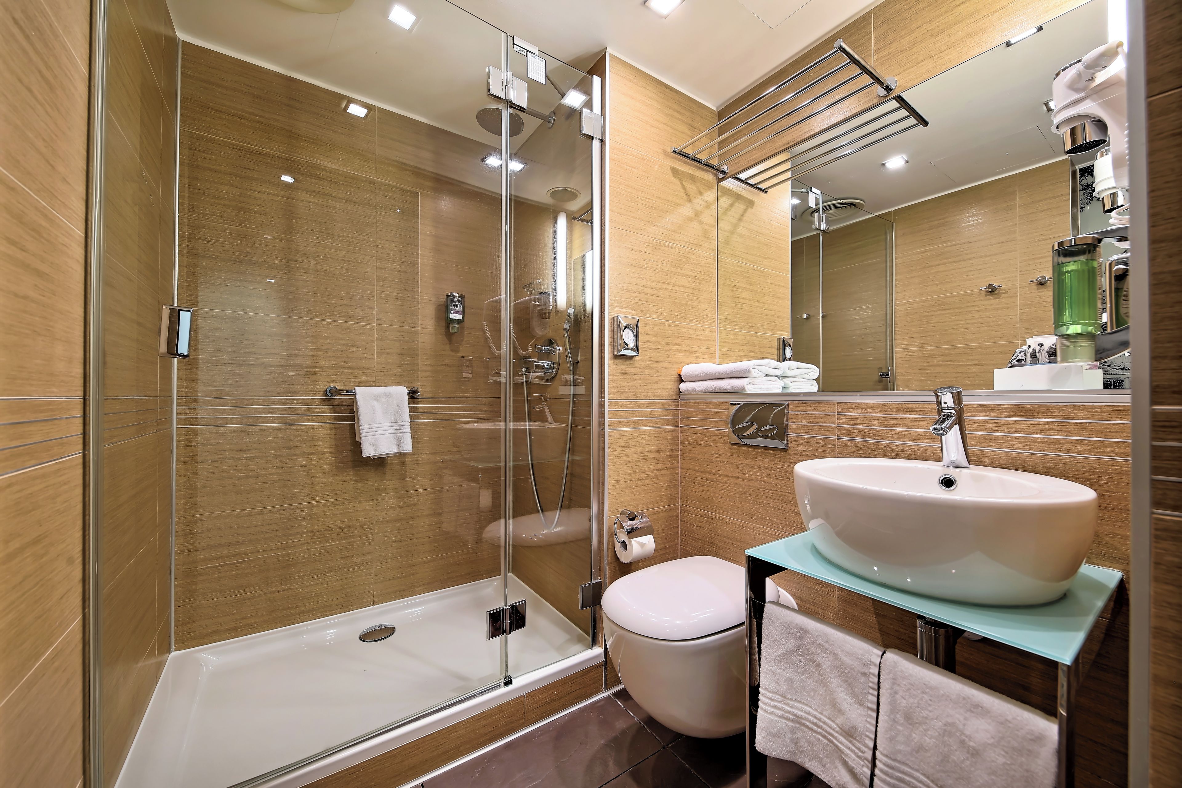 A modern bathroom with a glass-enclosed shower, a white sink, and a toilet.