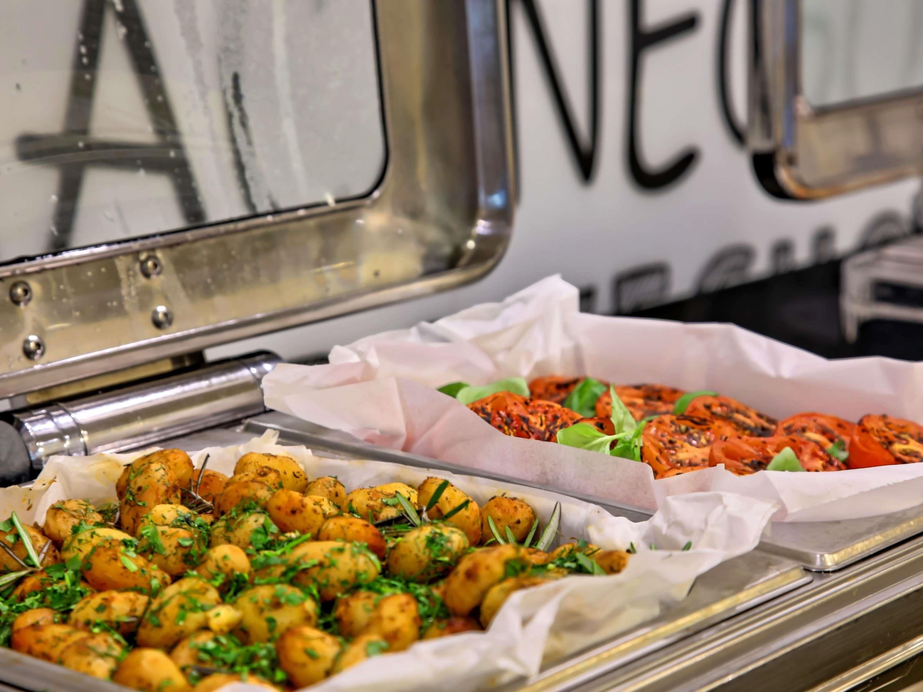 A buffet with roasted potatoes and grilled tomatoes.