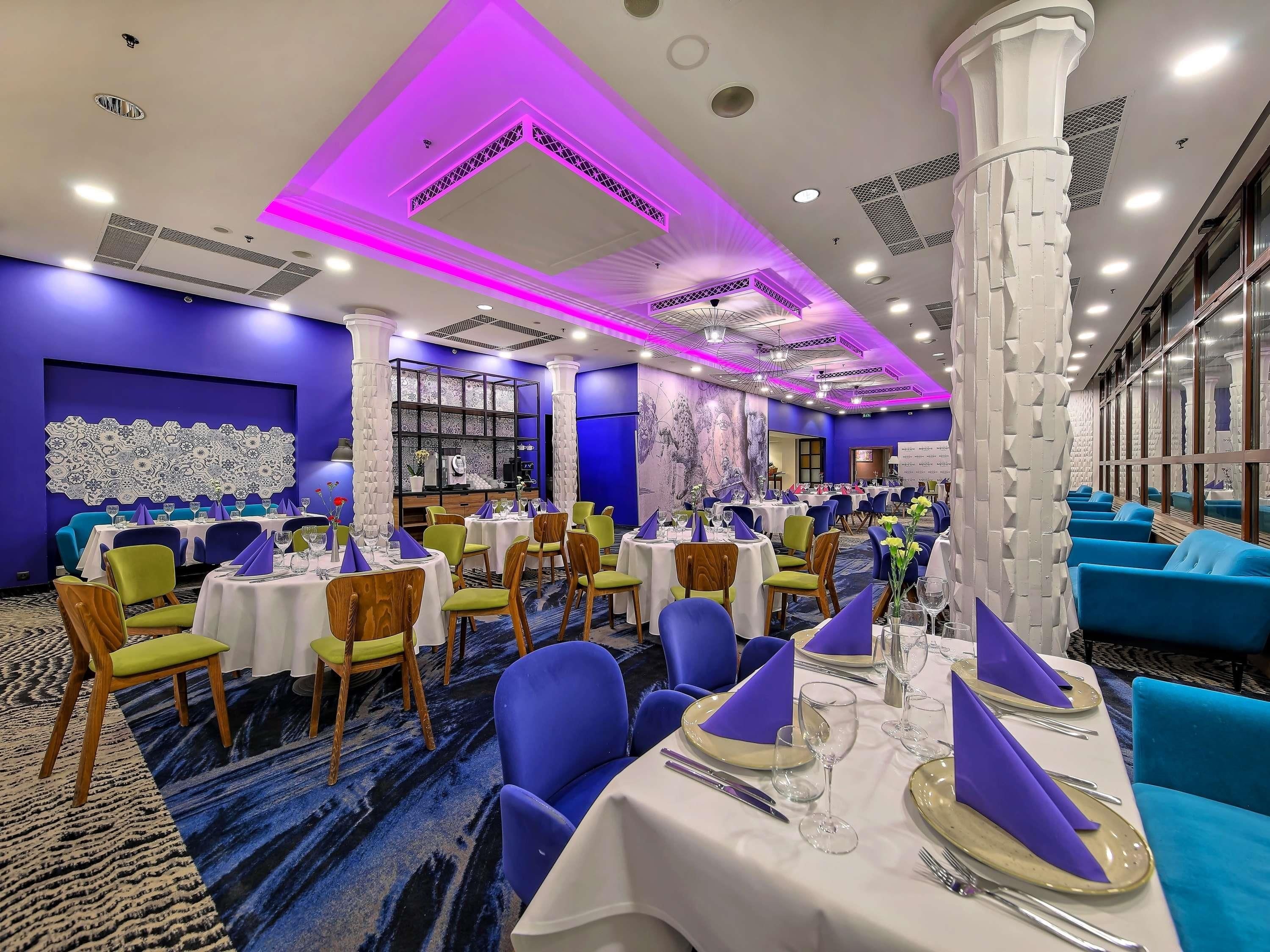 A dining area with tables set for service, chairs, and a decorative wall.