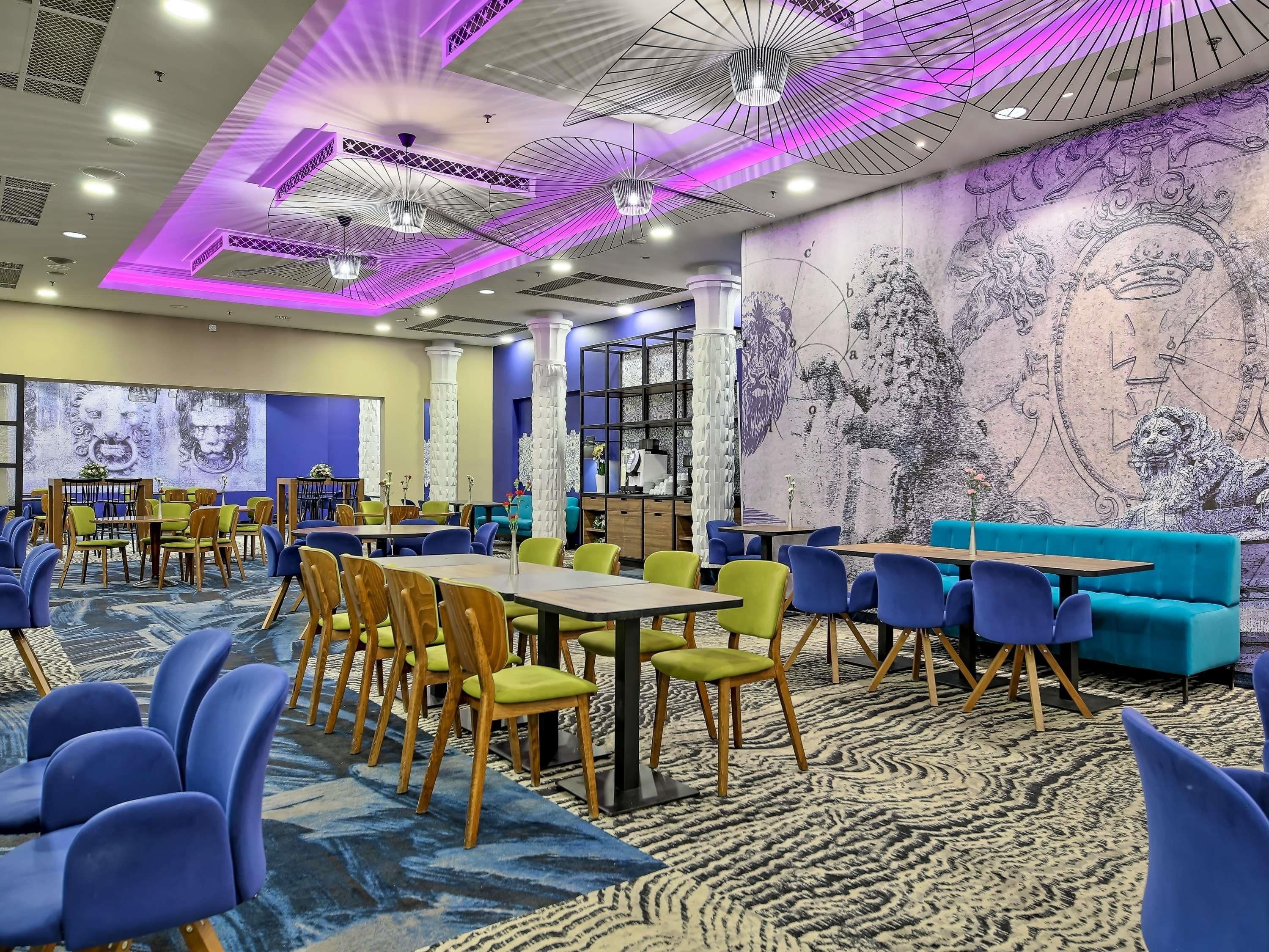 A modern dining area with tables and chairs, a patterned carpet, and a mural on the wall.