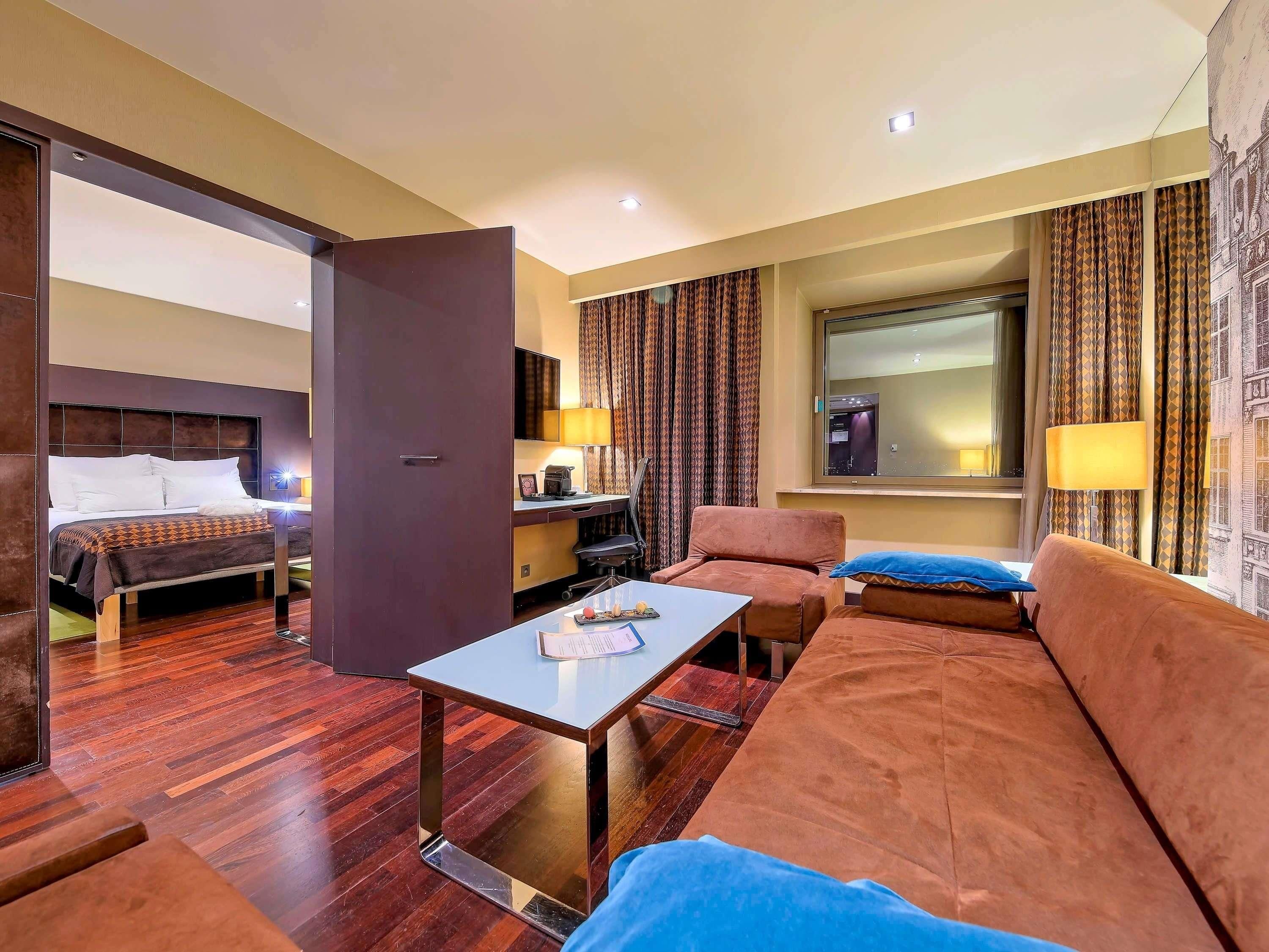 A hotel room with a bed, a sofa, a desk, and a chair.