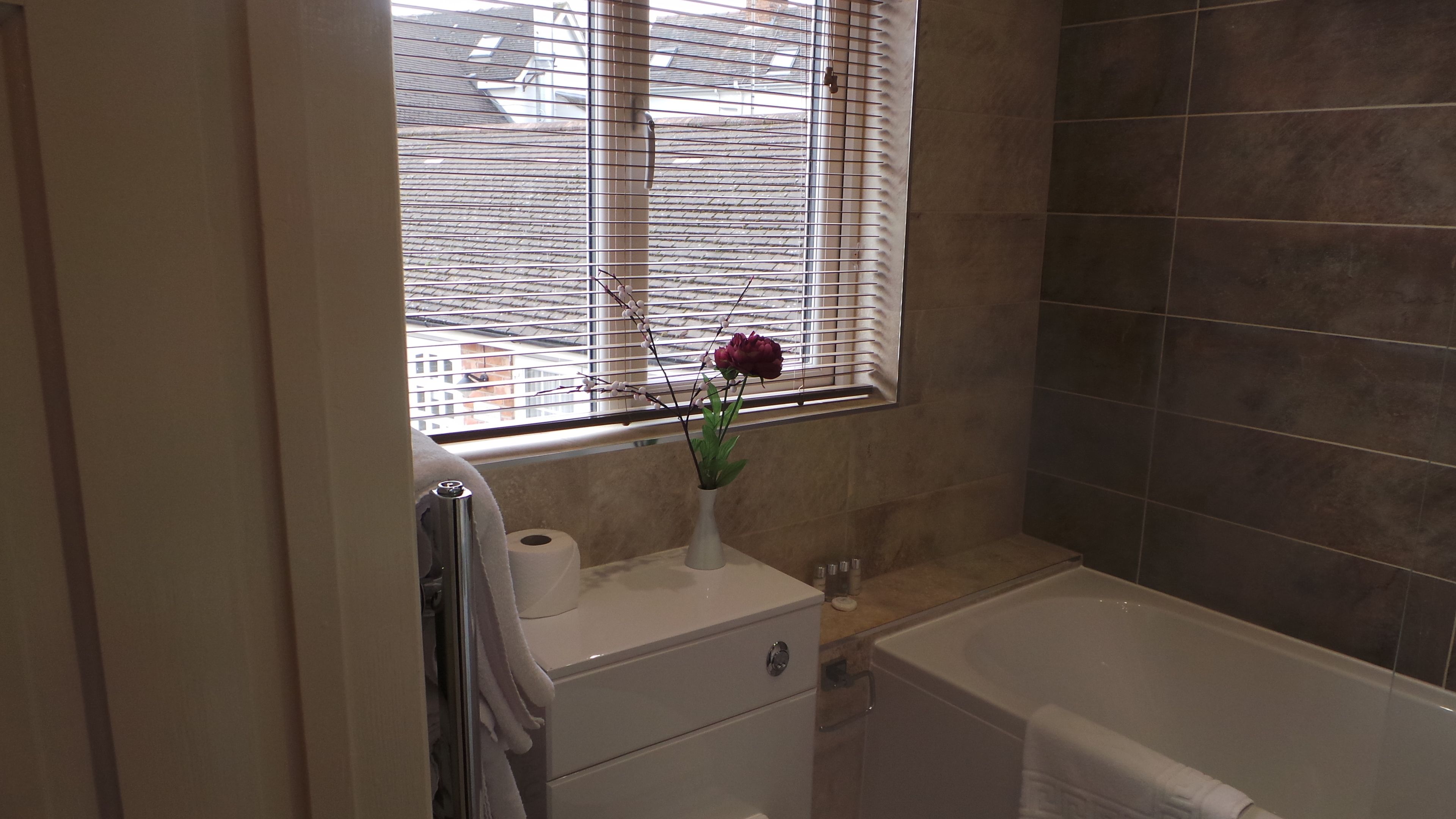 A bathroom with a bathtub, a toilet, a sink, and a window with blinds.