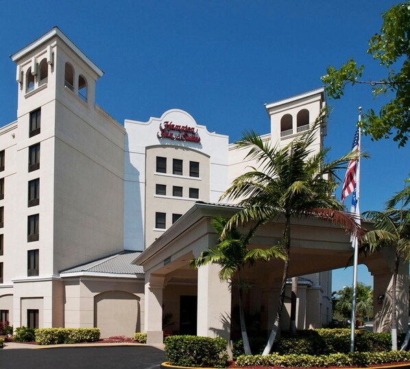 A hotel with a prominent sign, a flag, and a clear sky.