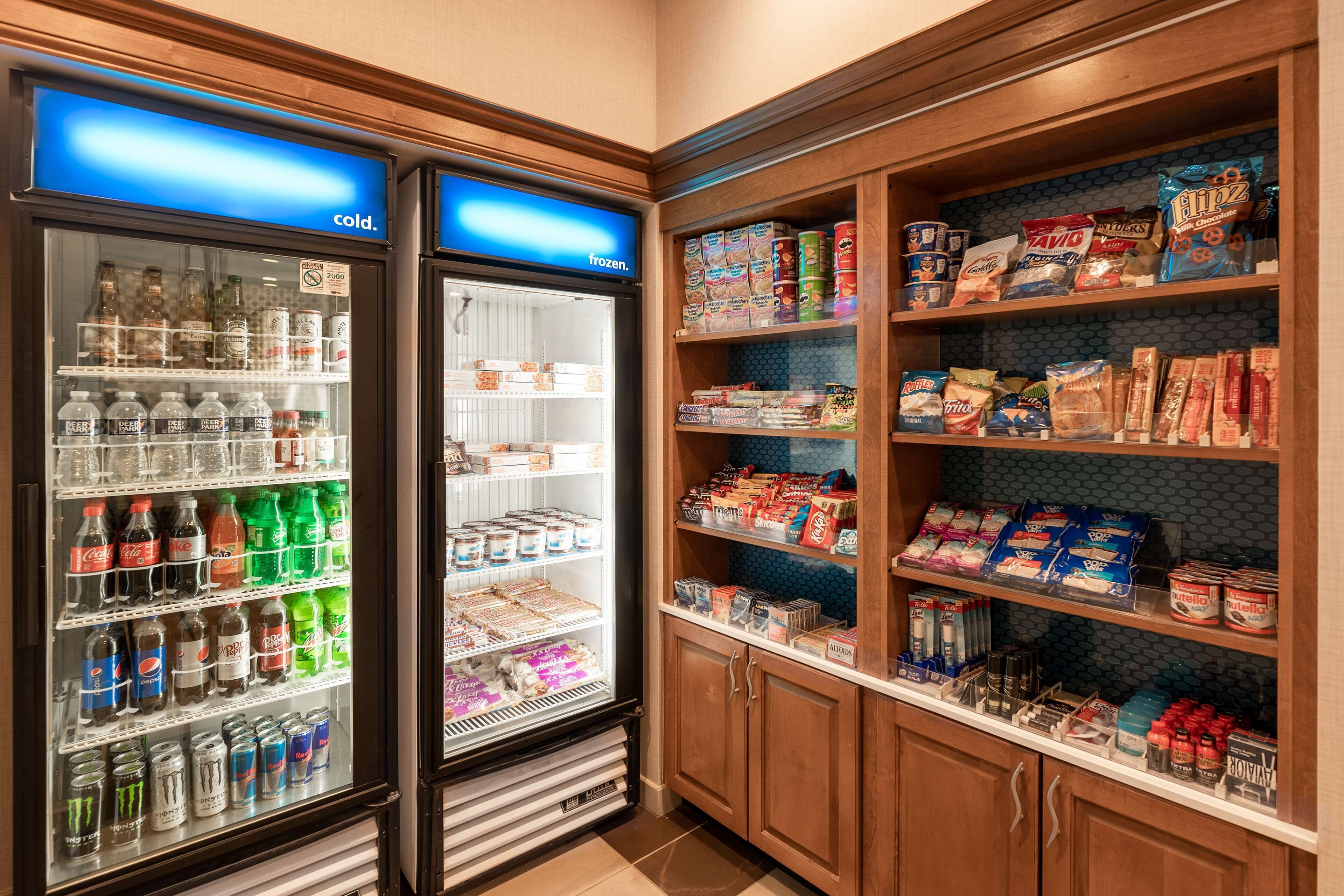 A self-service beverage station with refrigerated and frozen options, and shelves stocked with snacks and beverages.