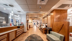 A hotel lobby with a reception desk, a sofa, a patterned rug, and a hallway leading to other rooms. - Hampton Inn Christiansburg/Blacksburg (Christiansburg)