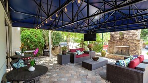 An outdoor patio with wicker furniture, a stone fireplace, and a TV mounted on the wall. - Hampton Inn Christiansburg/Blacksburg (Christiansburg)