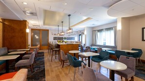 A hotel lobby with multiple seating areas, including booths and tables, and a bar in the center. - Hampton Inn Christiansburg/Blacksburg (Christiansburg)