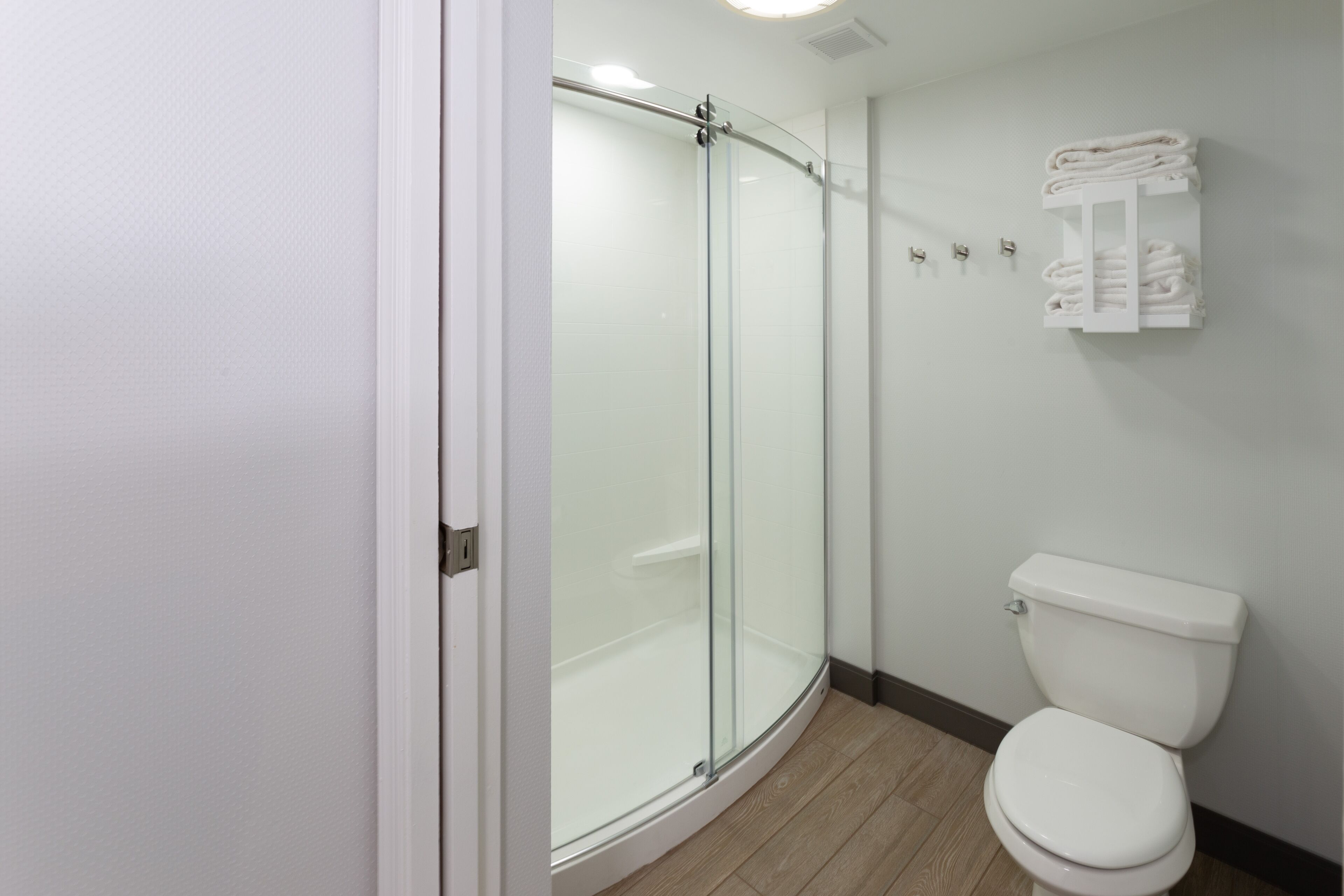 Un baño con ducha de vidrio, inodoro y toallero.