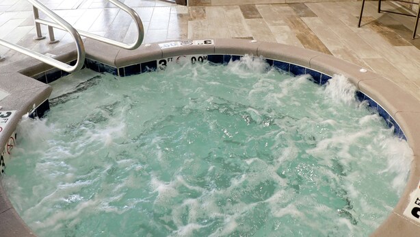 Un bain à remous avec une échelle en métal et un bord carrelé.