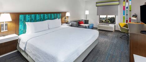 Une chambre d’hôtel avec un grand lit, un bureau avec une chaise, une télévision et une fenêtre donnant sur un beau paysage.