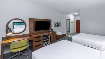 A hotel room with a bed, a desk with a computer, a TV, a mirror, and a small bathroom.