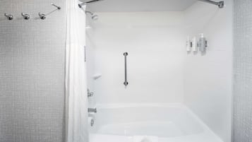 A modern bathroom with a walk-in shower, a bathtub, and a handrail.