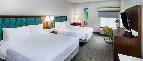 A hotel room with two beds, a desk, a chair, and a television.