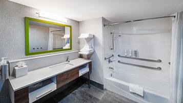 A modern bathroom with a large mirror, white sink, and a walk-in shower.