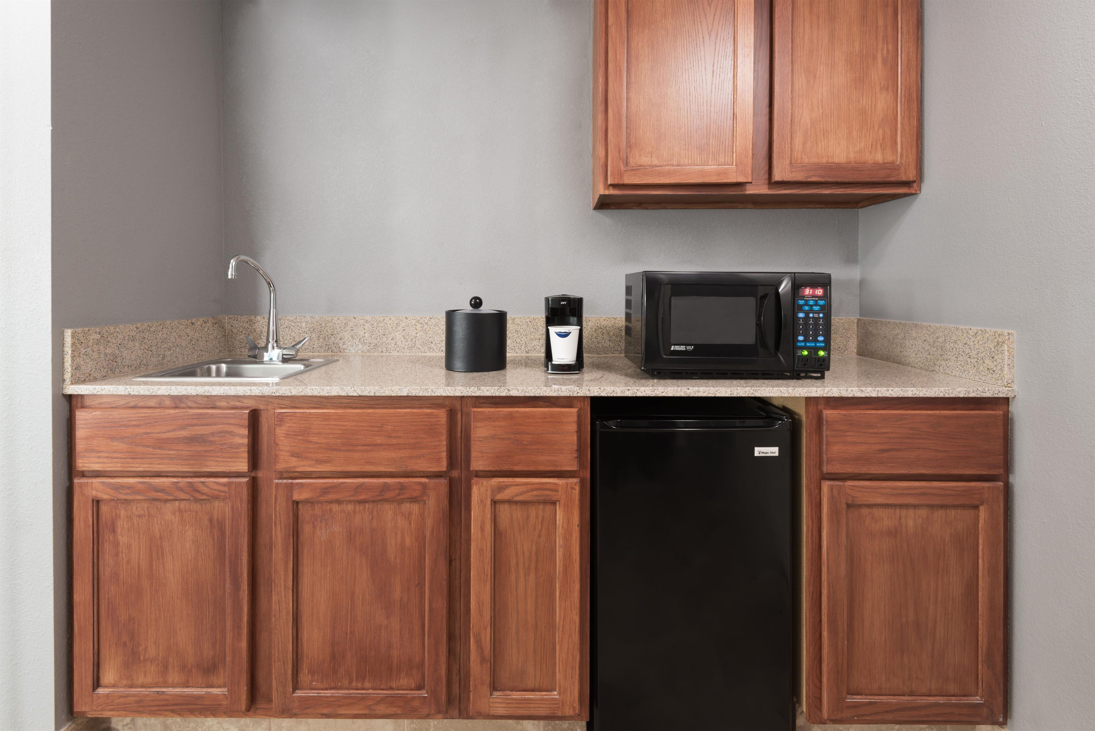 A kitchen with a sink, a coffee maker, a microwave, and a dishwasher.