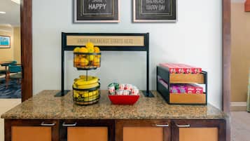 A breakfast station with fruit, cereal, and a sign that says 'Happy Breakfast Starts Here'.