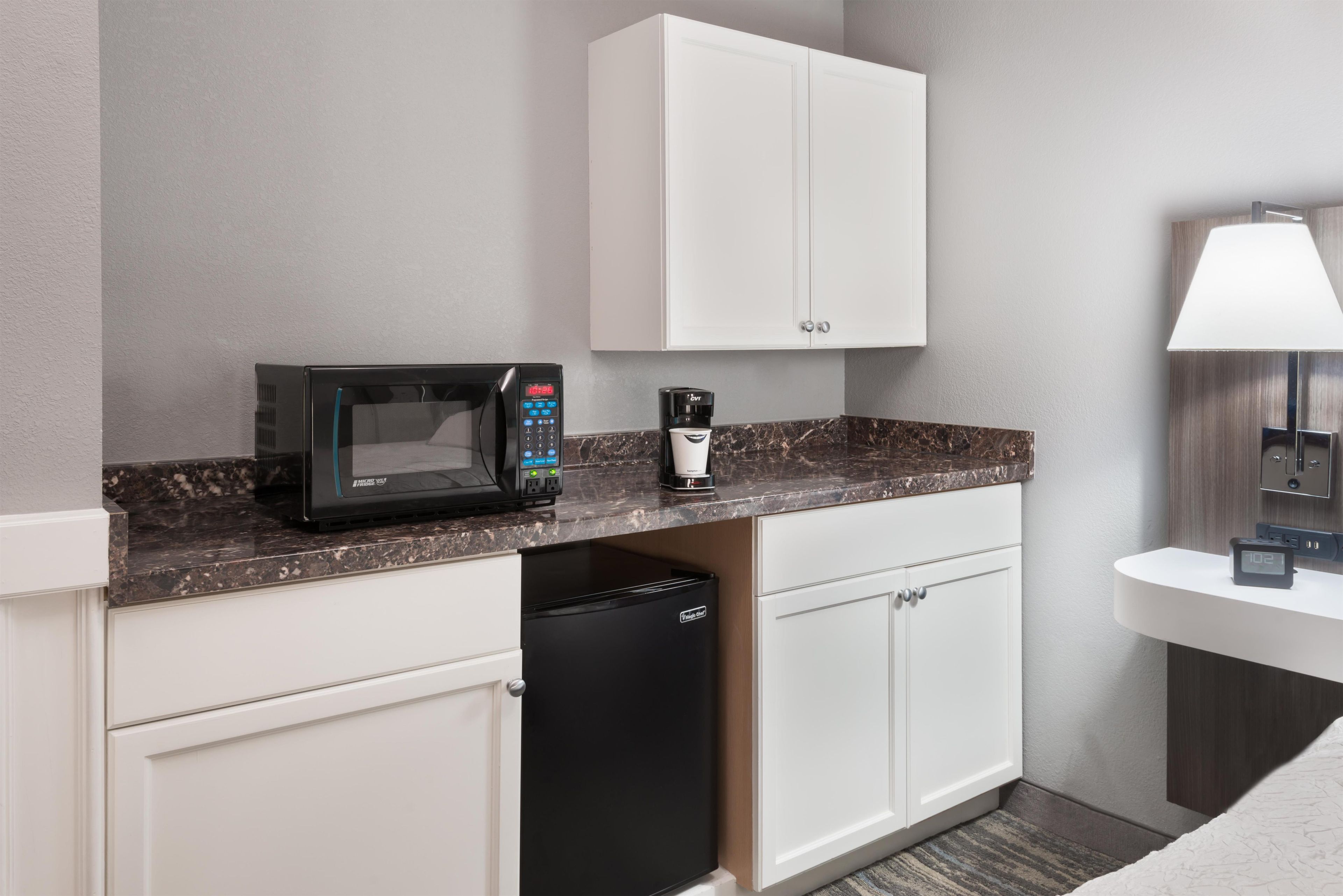 A compact kitchenette with a microwave, coffee maker, and dishwasher.