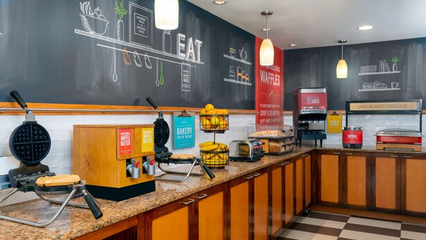 A breakfast bar with waffle makers, a juice station, and a waffle station. - Hampton Inn Ellenton/Bradenton (Ellenton)