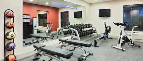 A gym with various exercise equipment, including benches, dumbbells, and a stationary bike.