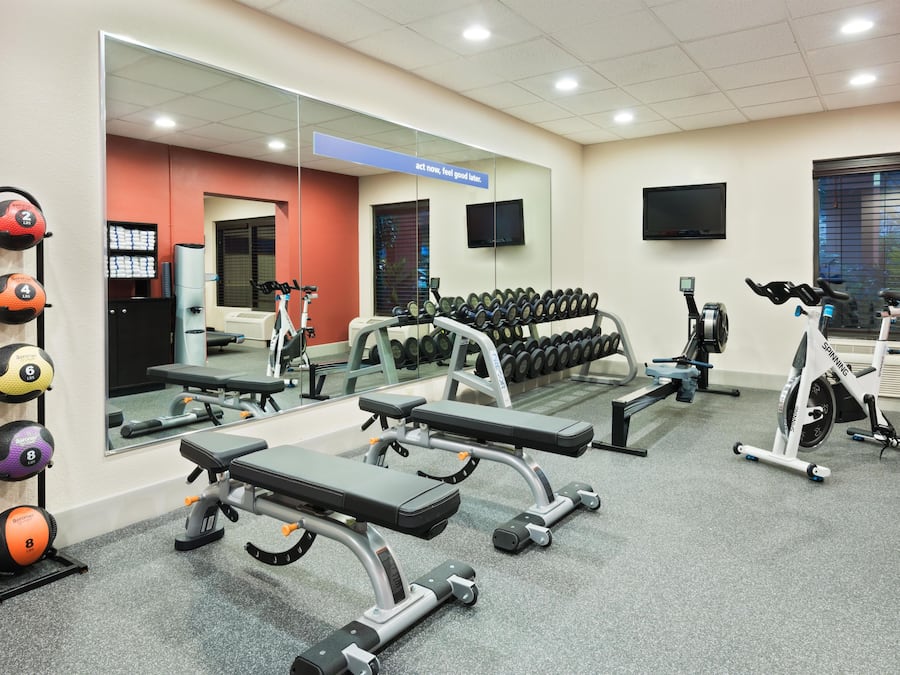 Un gimnasio con equipo de ejercicio variado, incluyendo bancos, mancuernas y una bicicleta estática.