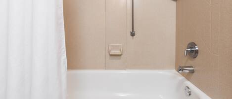 A white bathtub with a handheld showerhead, a wall-mounted faucet, and a corner grab bar.