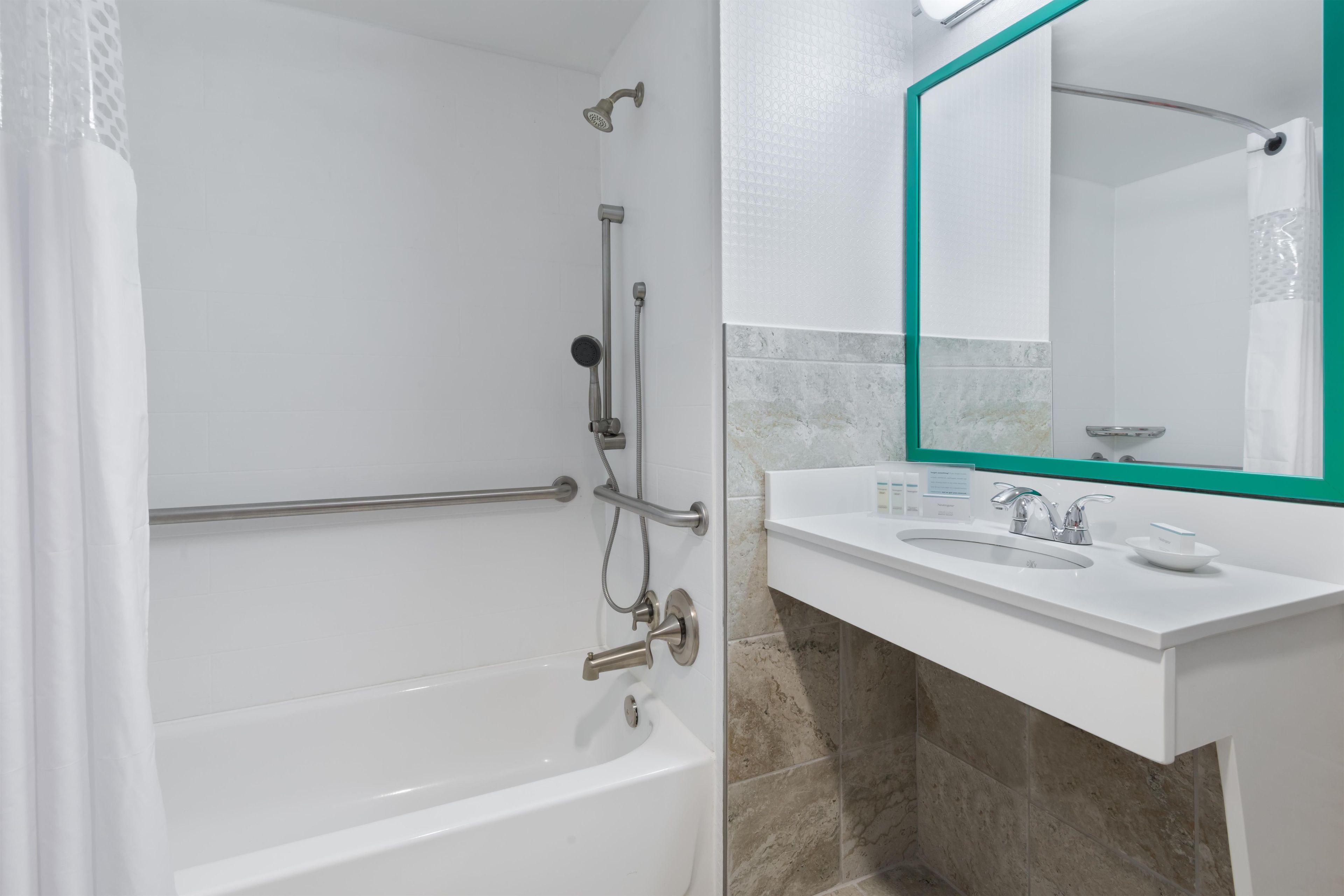 Un baño moderno con bañera, ducha y tocador con lavamanos y espejo.