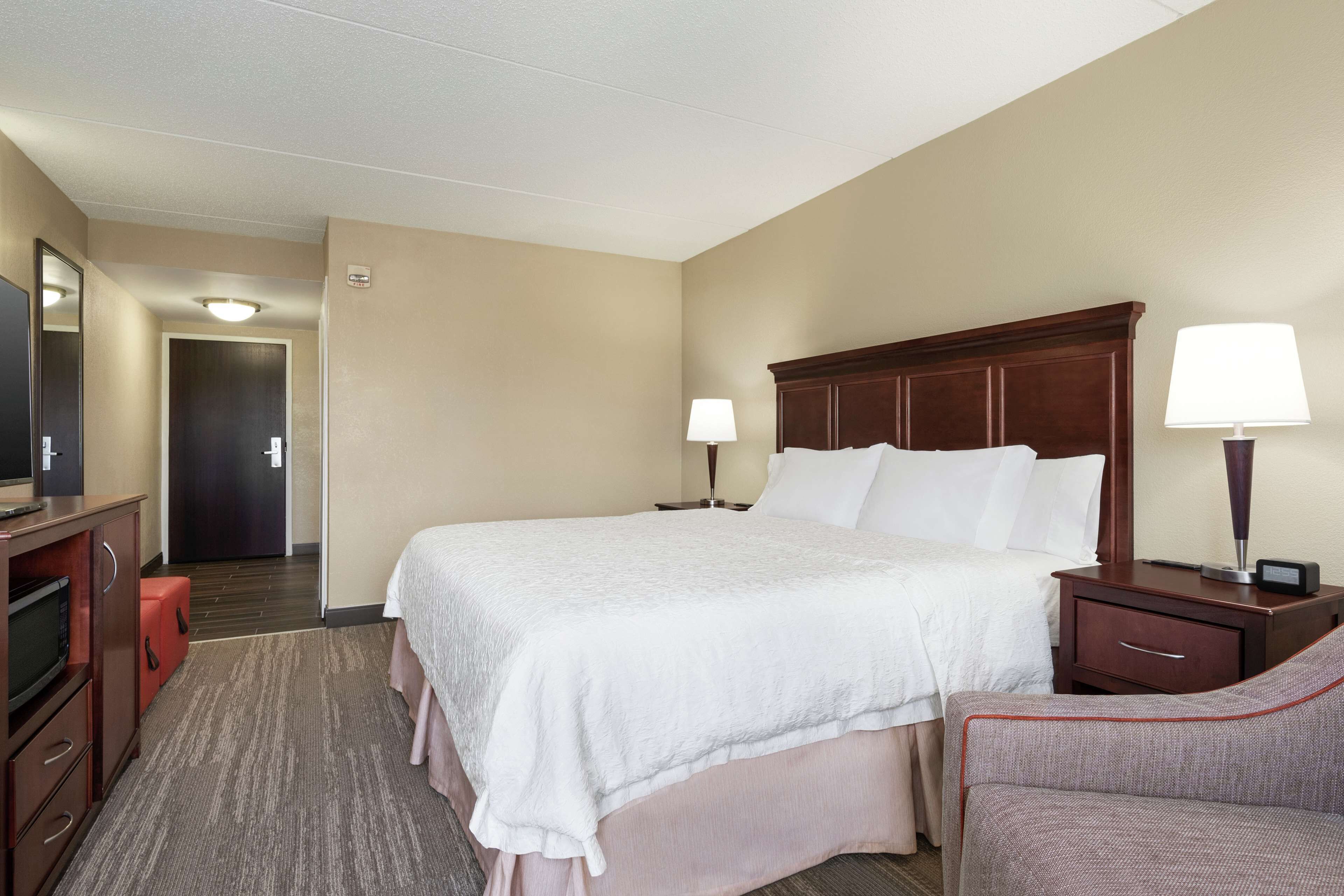 Une chambre d’hôtel avec un grand lit, un bureau avec une lampe, une chaise et un téléviseur.