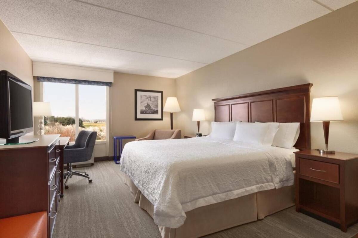 Ein Hotelzimmer mit Bett, Schreibtisch, Stuhl und Fernseher.