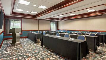 A conference room with a long table, multiple chairs, and a podium.