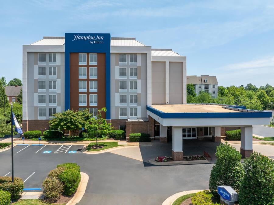 A Hampton Inn by Hilton hotel with a parking lot, a gas station, and a landscaped entrance.