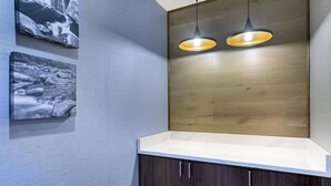 Un baño moderno con tocador de madera, dos lámparas colgantes y dos fotografías enmarcadas en la pared.