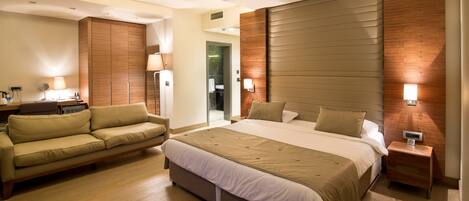 Une chambre d’hôtel moderne avec un grand lit, un canapé, une table de chevet et un mur décoratif en bois.