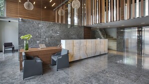 A modern reception area with a marble counter, wooden slats, and a staircase. - Hotel Arcadia Blue Istanbul (Istanbul)
