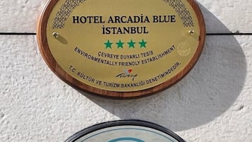 Zwei Schilder: eines für das Hotel Arcadia Blue Istanbul mit einer grünen Sterneinstufung und einem Umweltpreis, und ein weiteres für die Safe Tourism-Zertifizierung in der Türkei.
