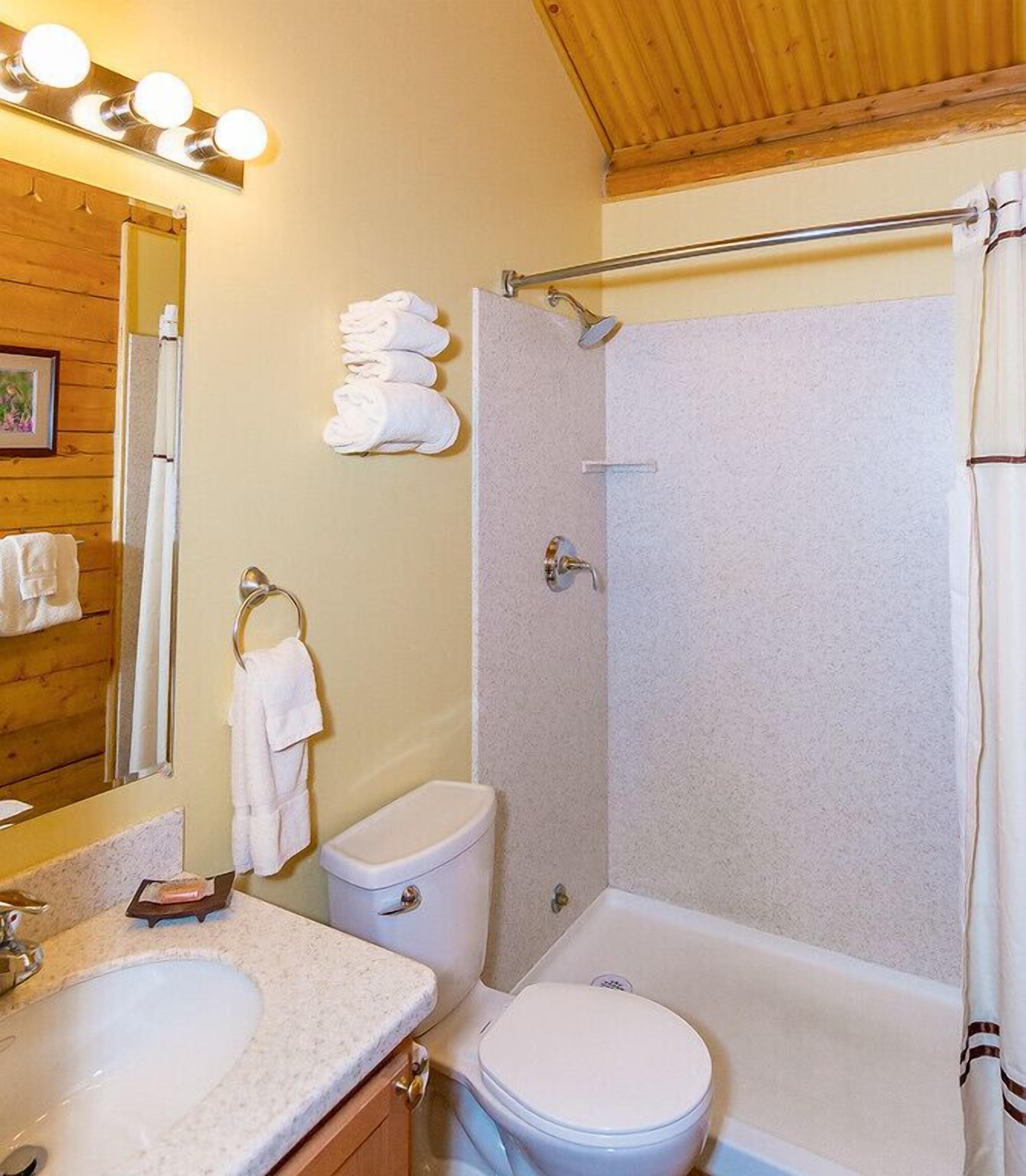Un baño con lavamanos, inodoro y bañera. Hay toallas colgadas en la pared y una cortina de ducha.