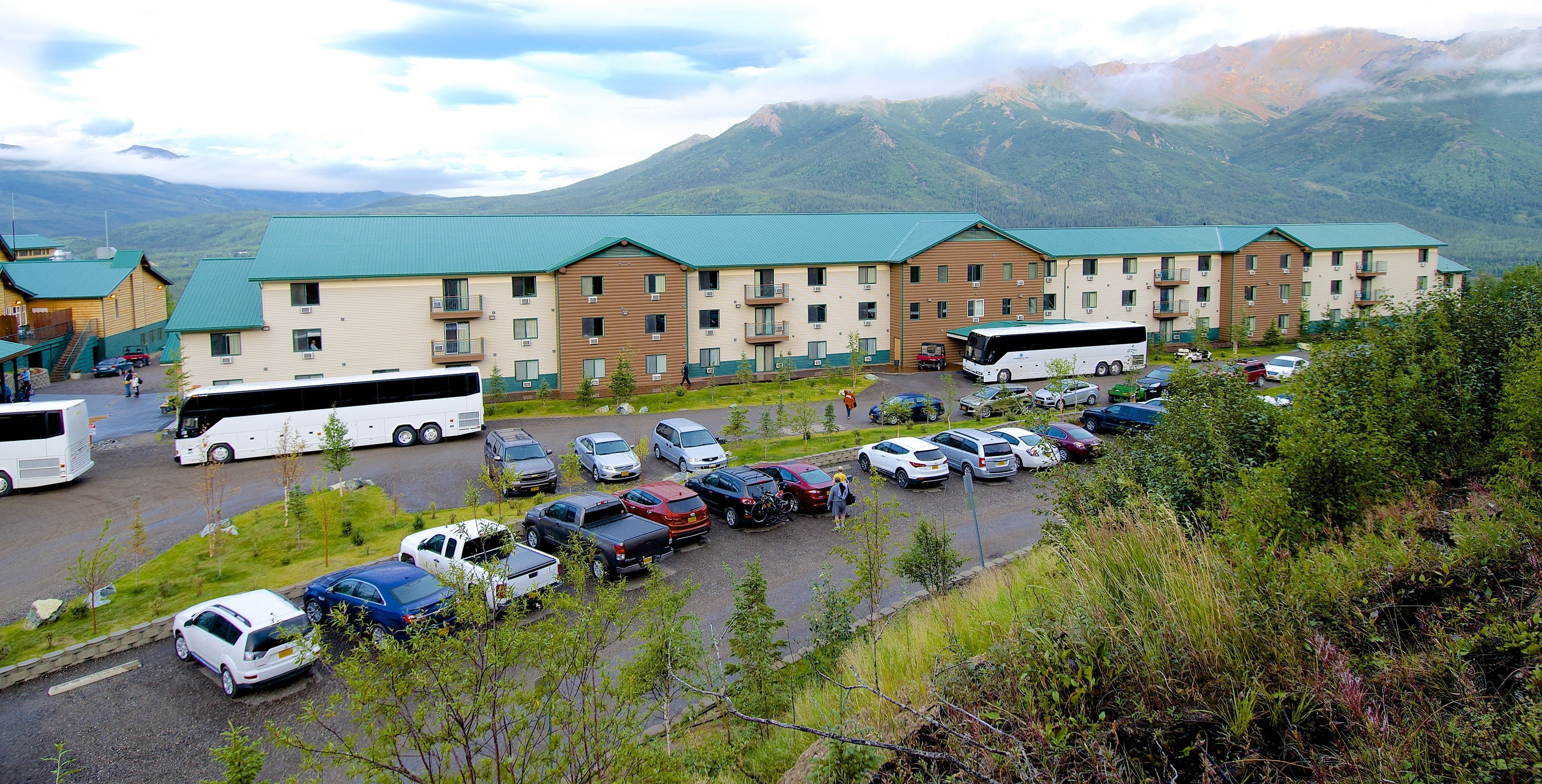 A hotel with multiple buildings, a parking lot, and a mountainous backdrop.