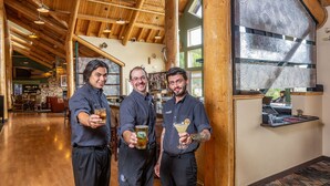 A wooden interior with high ceilings and hanging lights, a bar area with a counter, and a patterned window. - Grande Denali Lodge (Denali National Park)