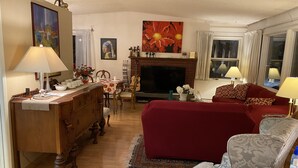 A living room with a fireplace, a dining area, and a television. - Alaska European Bed & Breakfast (Anchorage)