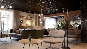 Un interior moderno con sofá, sillas, una mesa redonda e iluminación colgante.