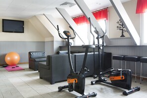 A fitness room with exercise equipment, a large exercise ball, and a TV on the wall. - Comfort Hotel Arctic (Luleå)