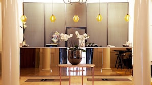 A reception area with a modern design, featuring a reception desk, a large vase with flowers, and a seating area with a table and chairs. - Elite Stora Hotellet Linköping (Linkoping)