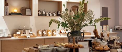 Una vitrina de panadería con pasteles, un jarrón de flores y diversos alimentos.