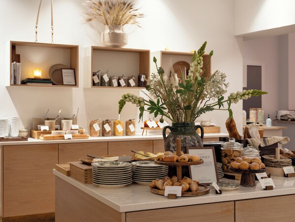 A bakery display with pastries, a vase of flowers, and various food items.