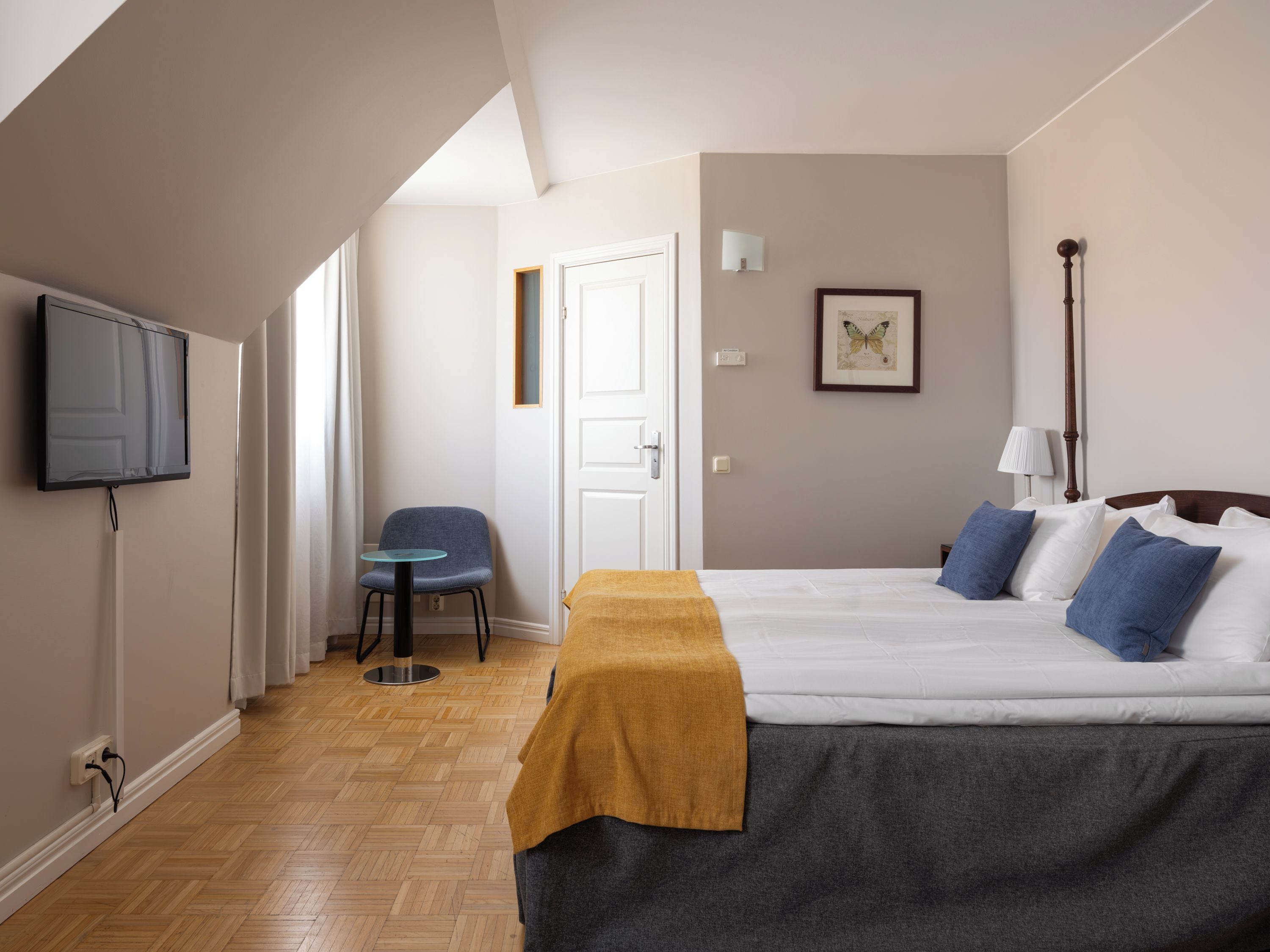Ein Hotelzimmer mit Bett, Fernseher, Stuhl und Tür.