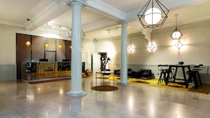 A spacious lobby with a modern kitchen area, a seating area with a table and chairs, and decorative lighting. - Elite Stora Hotellet Linköping (Linkoping)