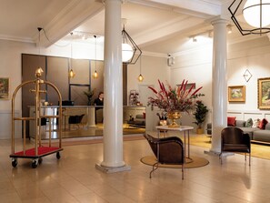 A spacious lobby with a reception desk, a gold cart, and a seating area with a round table and chairs. - Elite Stora Hotellet Linköping (Linkoping)