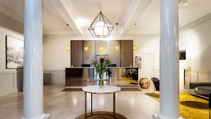 A spacious lobby with a reception desk, a round table with a vase, and a modern chandelier. - Elite Stora Hotellet Linköping (Linkoping)